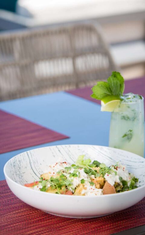 a bowl of food and a cocktail on a outside table